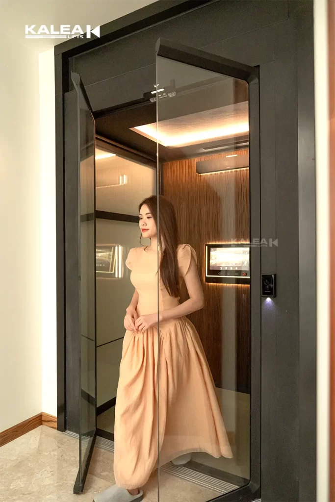 Antera Lift dengan pintu Saloon door kaca di samping tangga rumah modern