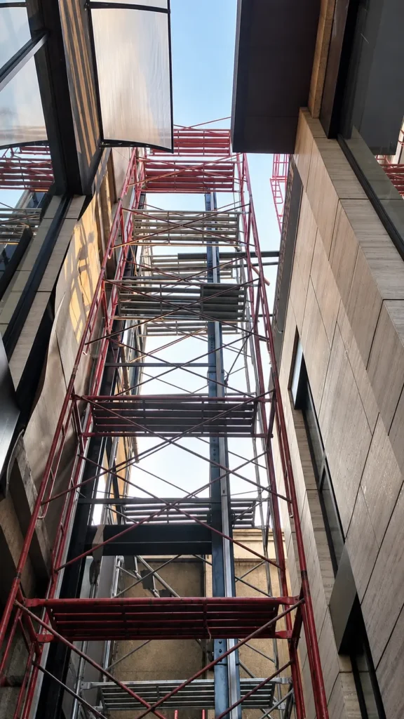 Scaffolding pada proses pemasangan lift di area outdoor bangunan bertingkat
