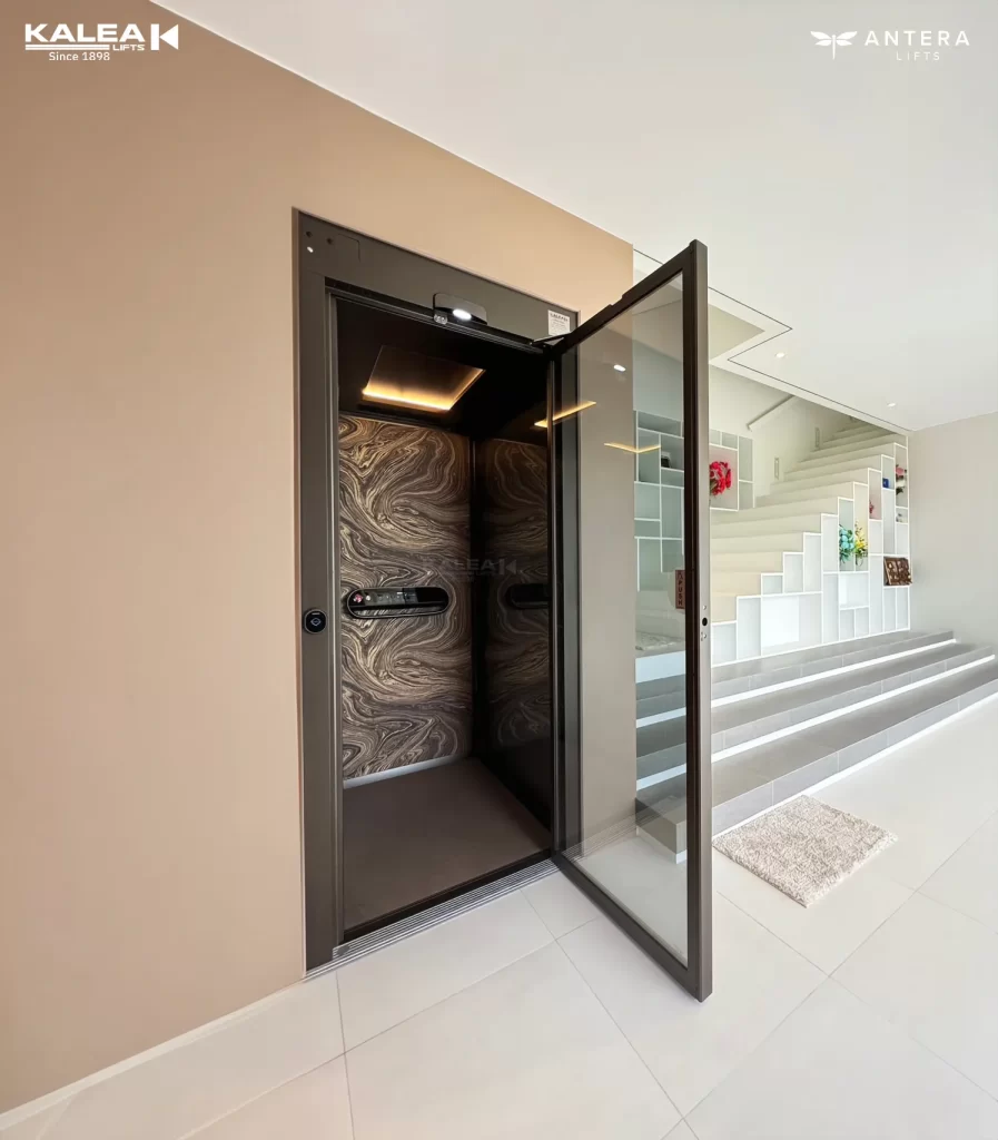 Lift rumah Kalea dengan pintu swing door di area ruang keluarga terang