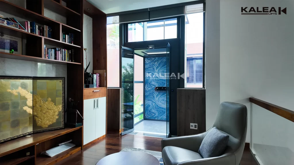 Checklist Pasang Lift Rumah: 15 Hal Penting 7 Kalea home lift dengan pintu terbuka di samping area baca dan furnitur rumah