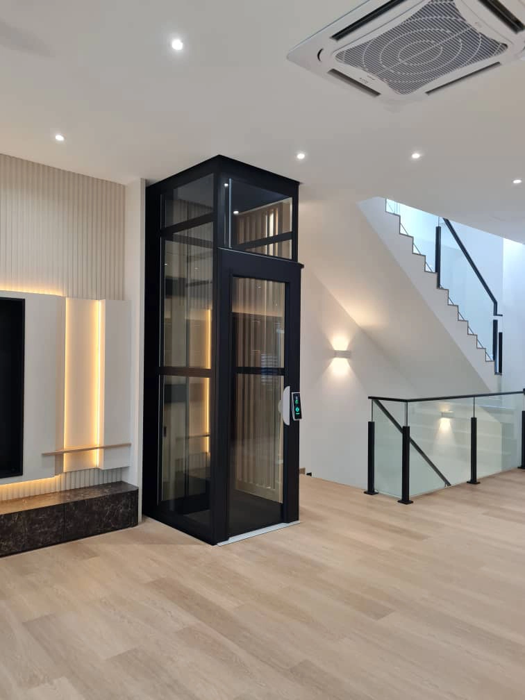 Lift rumah Kalea KOSMOS K90 dengan rangka hitam dan panel kaca diintegrasikan di samping tangga rumah modern minimalis 