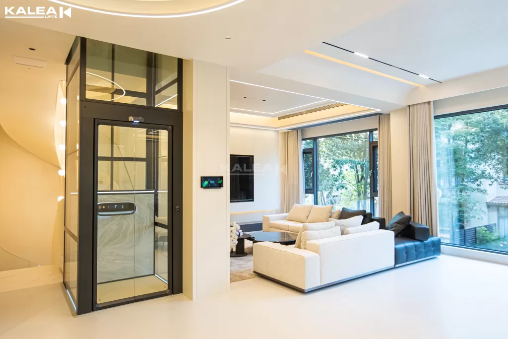 Kalea X50 Premium Pro di ruang keluarga modern dengan shaft kaca, menunjukkan lift rumah premium yang ringkas untuk kebutuhan teknis dan perencanaan ruang di hunian pribadi.