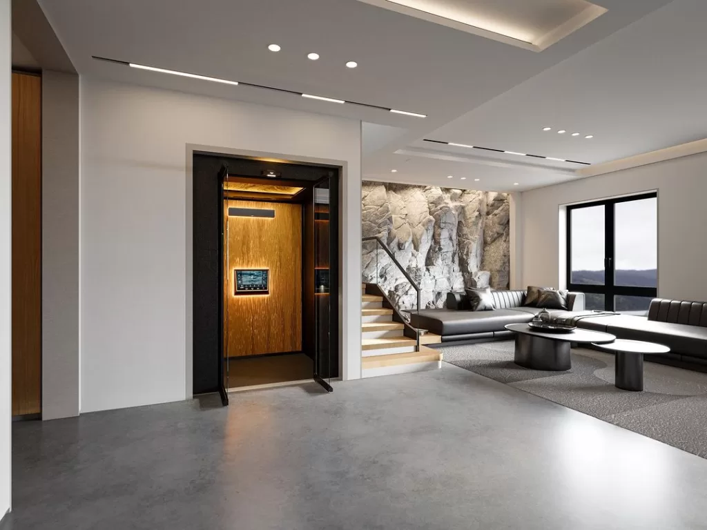 Lift rumah Antera Z70 dengan interior premium bernuansa hangat di ruang keluarga modern, menampilkan desain homelift eco-friendly yang menyatu dengan hunian mewah.
